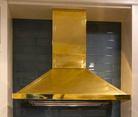 Polished brass range hood in a beautiful kitchen